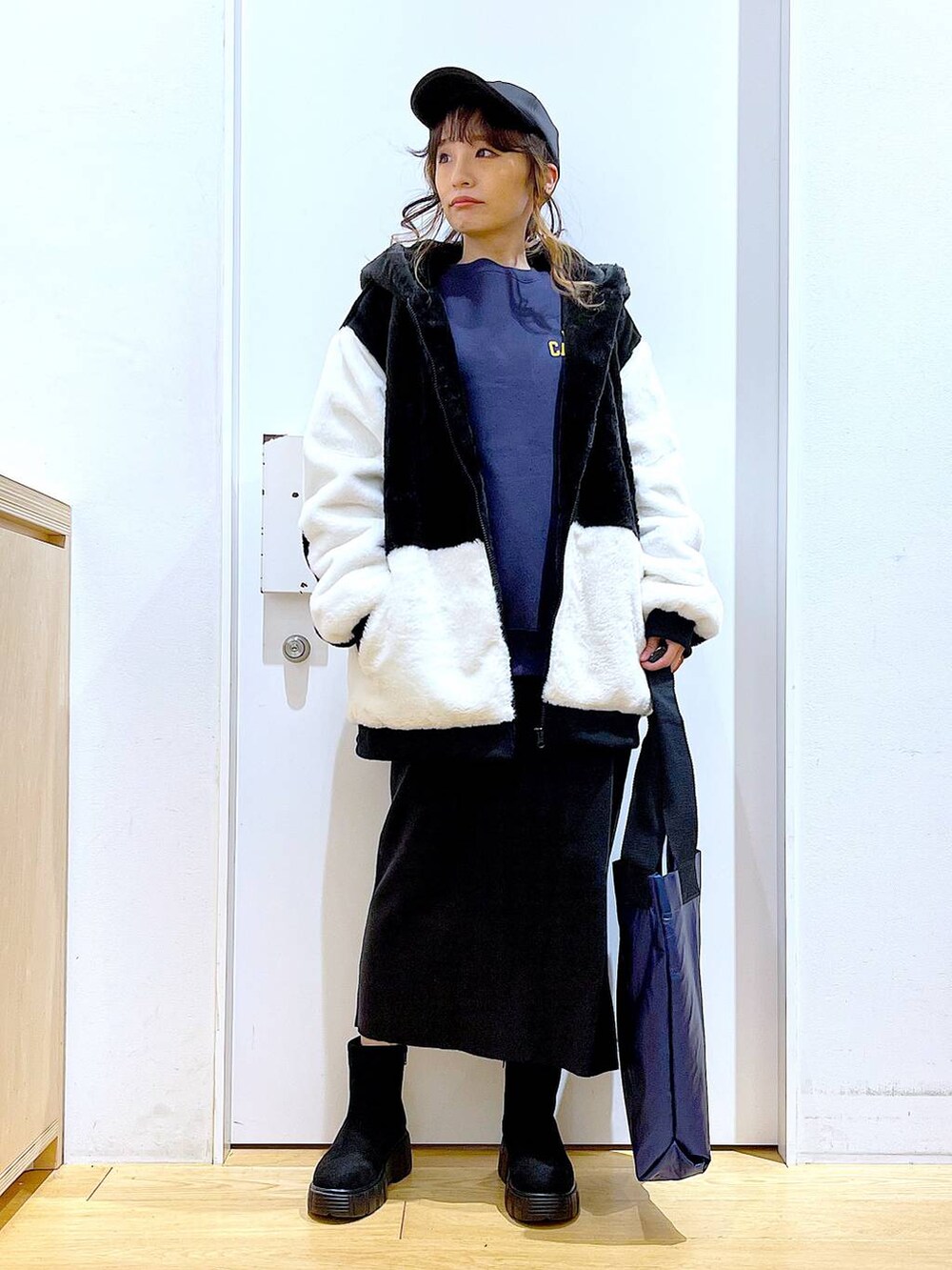 グレー系のスカート、ホワイト系のブルゾン、ブラック系のブーツを着用したレディースの冬コーディネートの2枚目の写真