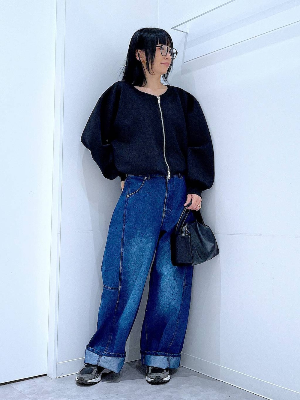 ブラック系のショルダーバッグ、ブルー系のデニムパンツ、ブラック系のスウェットを着用したレディースの春コーディネートの2枚目の写真