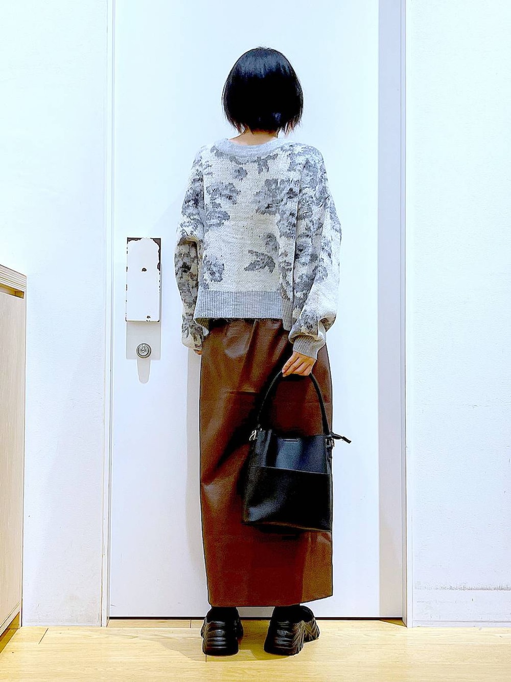 ブラウン系のスカート、ブラック系のショルダーバッグ、ブラック系のブーツを着用したレディースの冬コーディネートの5枚目の写真