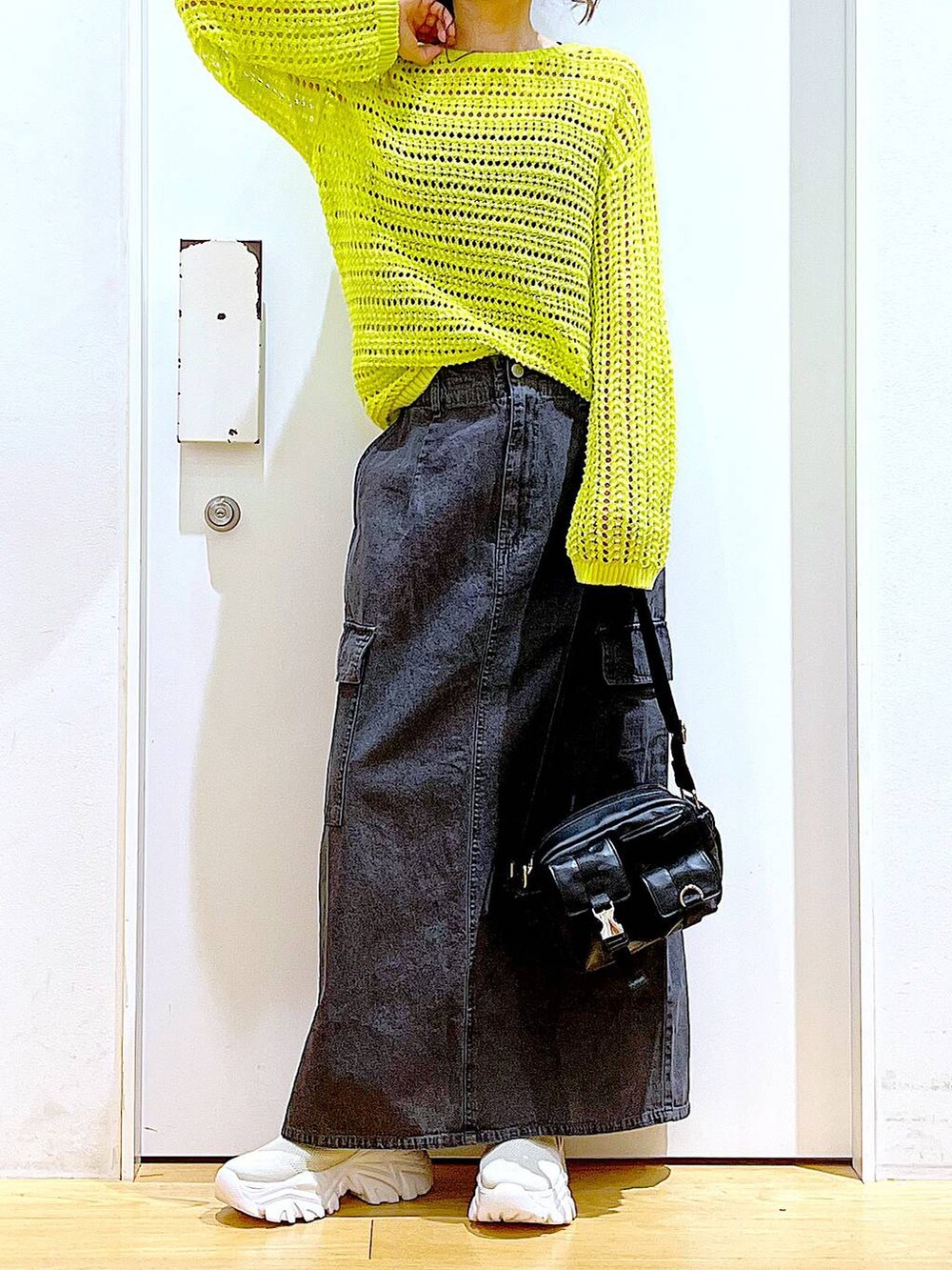 グレー系のデニムスカート、ベージュ系のスニーカー、ブラック系のショルダーバッグを着用したレディースの春コーディネートの6枚目の写真