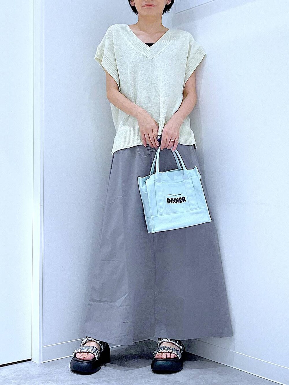 シルバー系のサンダル、グレー系のスカート、ホワイト系のベストを着用したレディースの夏コーディネートの6枚目の写真