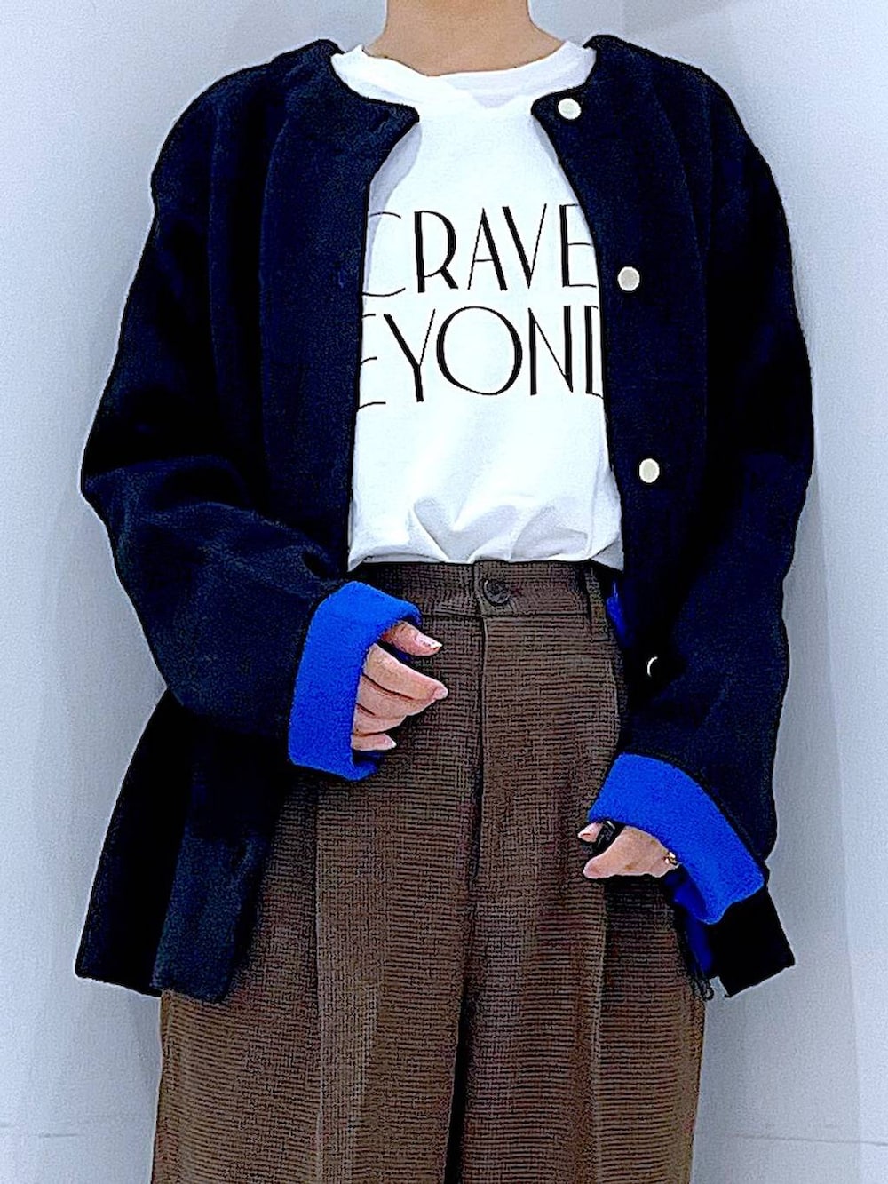 ブラック系のハンドバッグ、ブラウン系のスラックス、ホワイト系のTシャツ/カットソーを着用したレディースの秋コーディネートの7枚目の写真