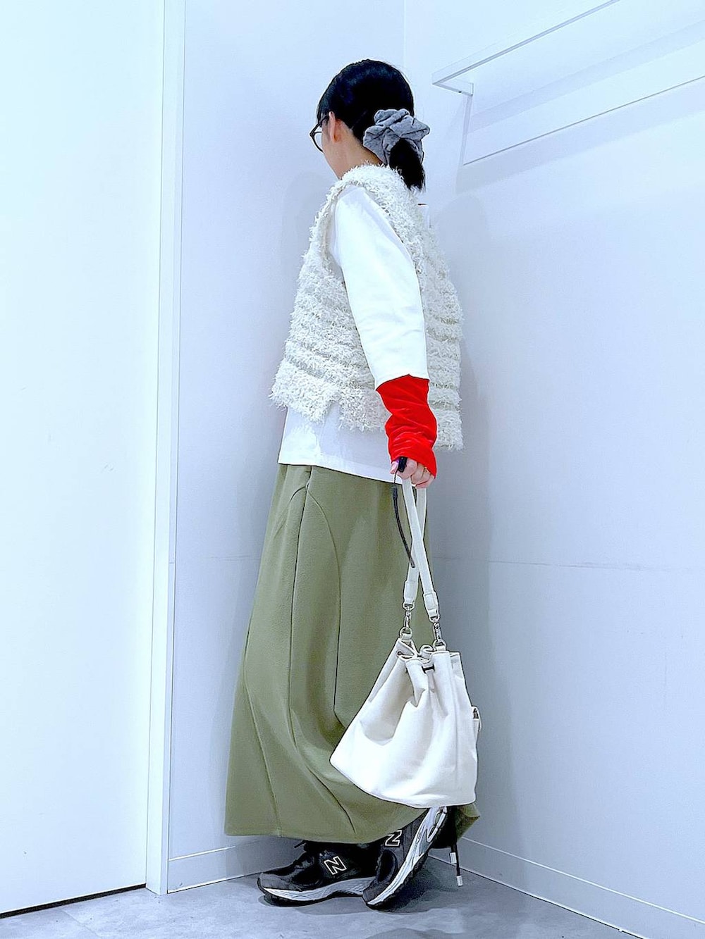 グリーン系のスカート、ホワイト系のTシャツ/カットソー、ベージュ系のベストを着用したレディースの冬コーディネートの3枚目の写真