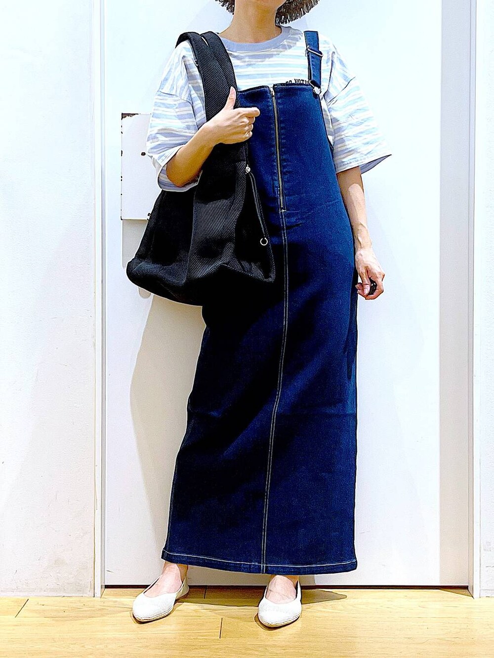 ホワイト系のパンプス、ブルー系のジャンパースカート、ブラック系のショルダーバッグを着用したレディースの夏コーディネートの6枚目の写真