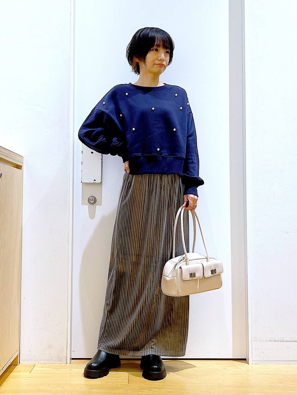 ホワイト系のハンドバッグ、ブラック系のブーツ、ブルー系のスウェットを着用したレディースの秋コーディネートの2枚目の写真
