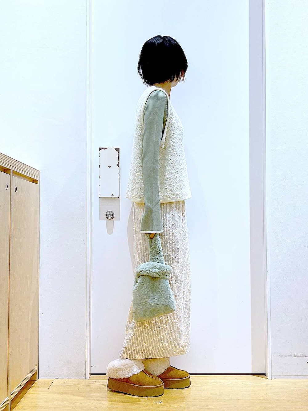 グリーン系のニット/セーター、グリーン系のショルダーバッグ、ベージュ系のベストを着用したレディースの秋コーディネートの4枚目の写真