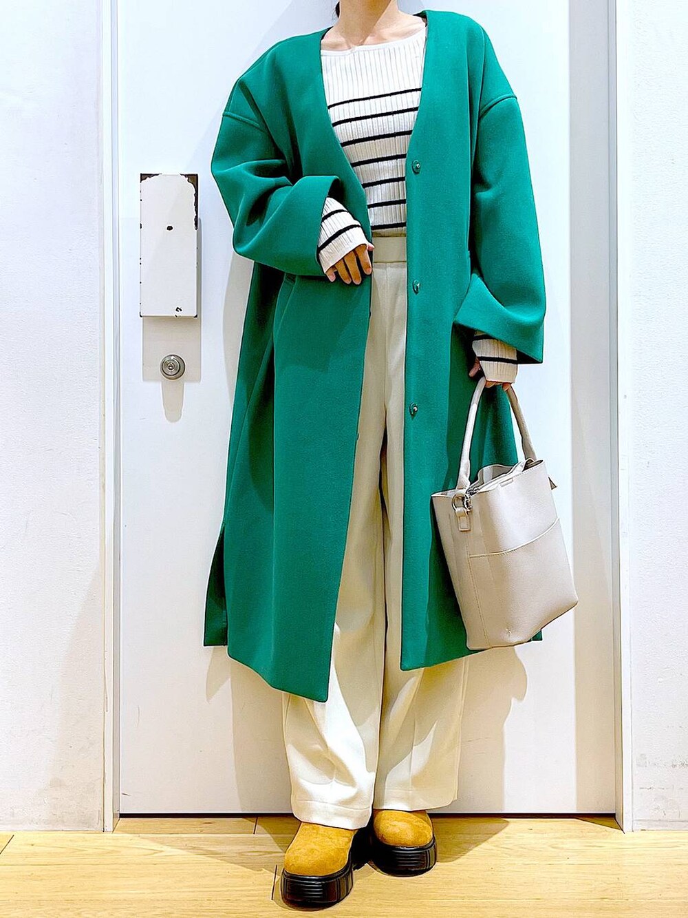 グレー系のショルダーバッグ、ホワイト系のニット/セーター、ベージュ系のブーツを着用したレディースの冬コーディネートの6枚目の写真