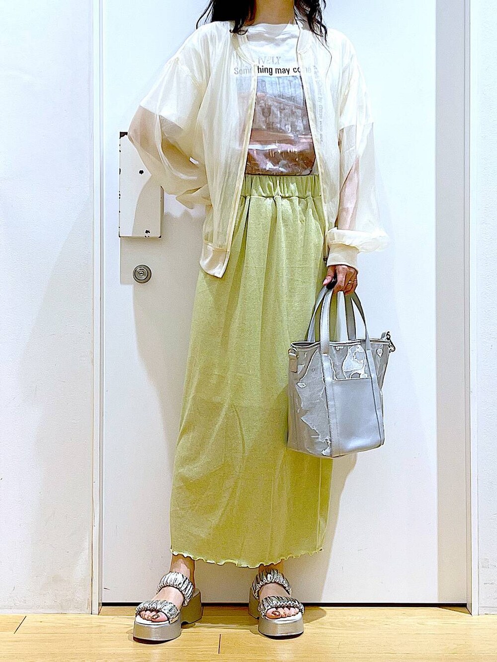 グリーン系のスカート、シルバー系のサンダル、シルバー系のトートバッグを着用したレディースの夏コーディネートの6枚目の写真