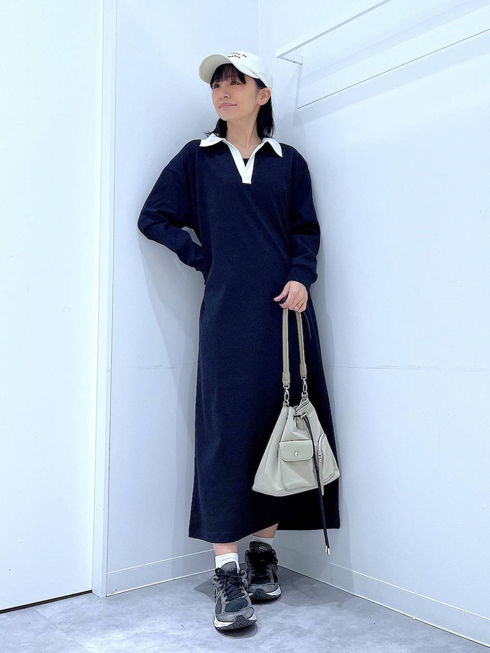 ホワイト系のショルダーバッグ、ブラック系のワンピース、ホワイト系のキャップを着用したレディースの春コーディネートの2枚目の写真
