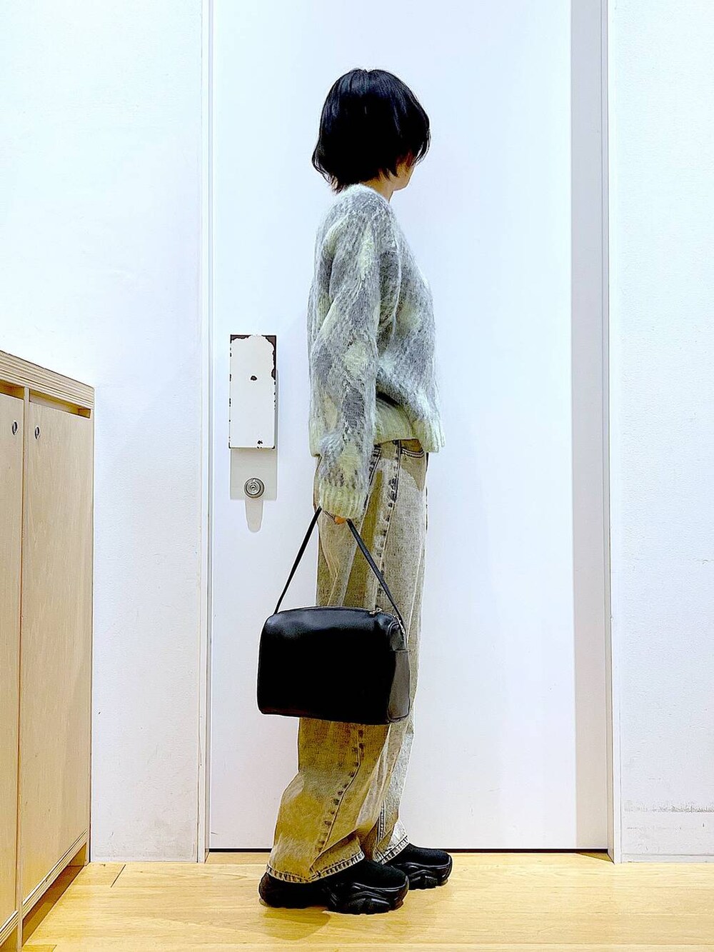 ブラック系のショルダーバッグ、ブラック系のブーツ、ベージュ系のデニムパンツを着用したレディースの冬コーディネートの4枚目の写真