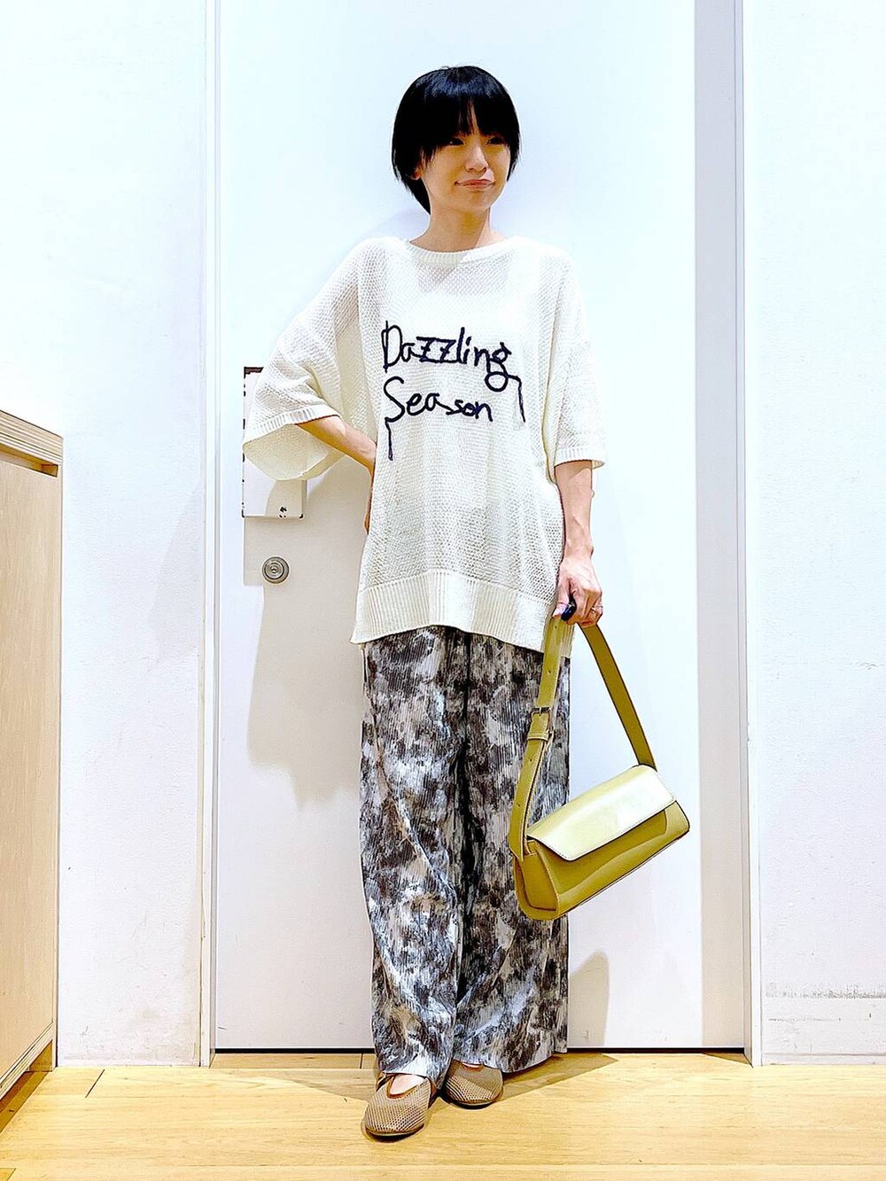 ベージュ系のパンプス、イエロー系のショルダーバッグ、グレー系のその他パンツを着用したレディースの春コーディネートの2枚目の写真