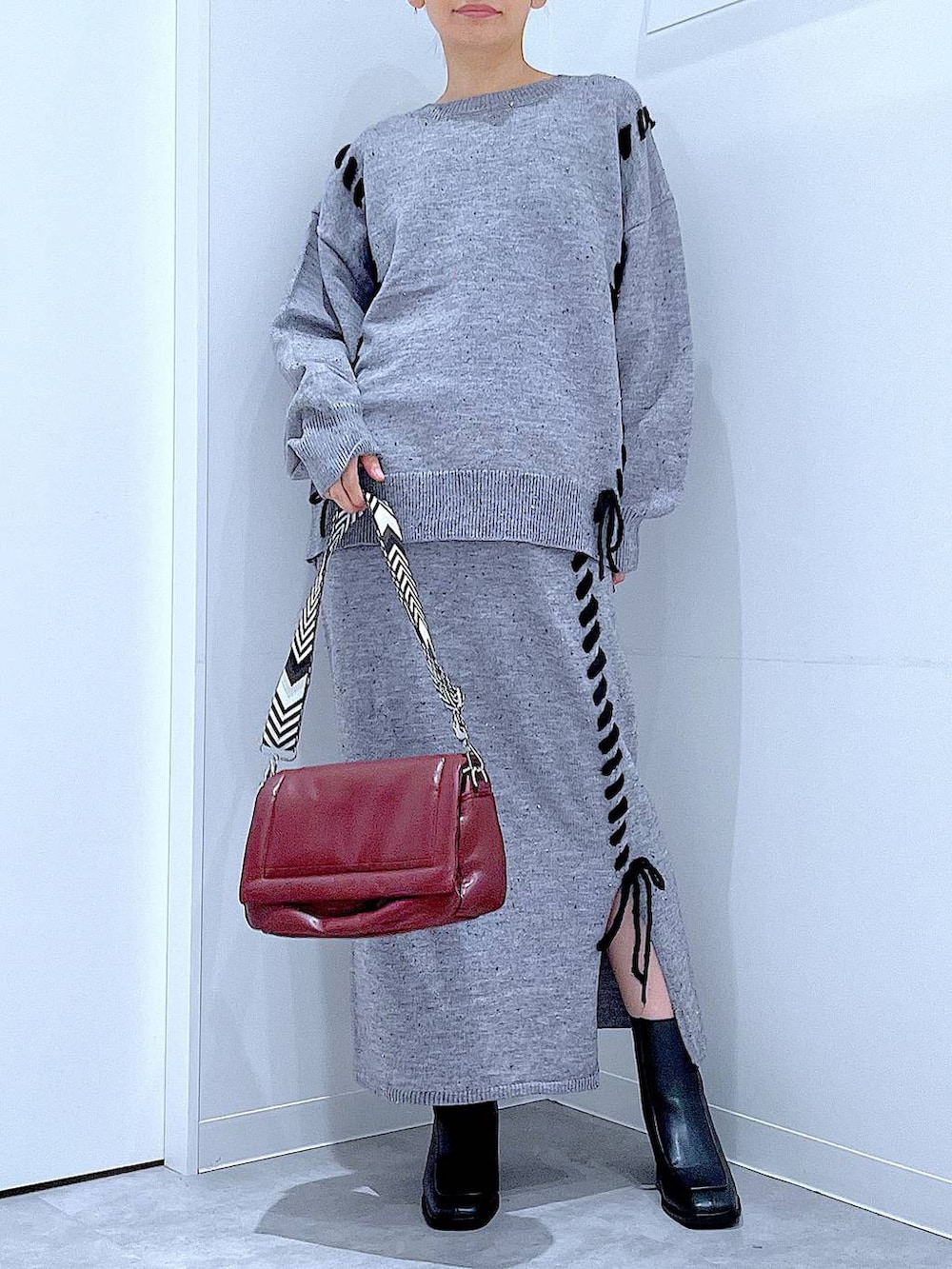 グレー系のニット/セーター、レッド系のショルダーバッグ、グレー系のスカートを着用したレディースの冬コーディネートの6枚目の写真