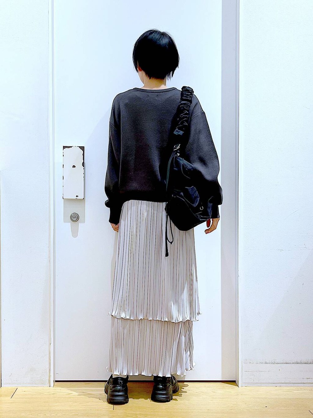 ブラック系のショルダーバッグ、ブラック系のスニーカー、グレー系のニット/セーターを着用したレディースの夏コーディネートの5枚目の写真