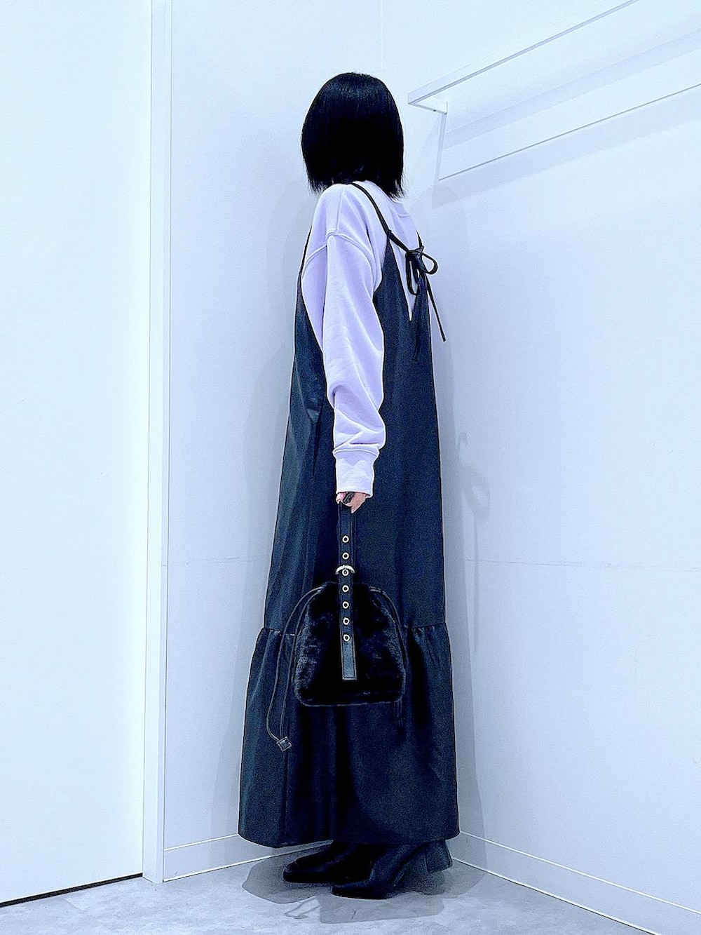 ブラック系のハンドバッグ、ブラック系のブーツ、パープル系のスウェットを着用したレディースの冬コーディネートの3枚目の写真