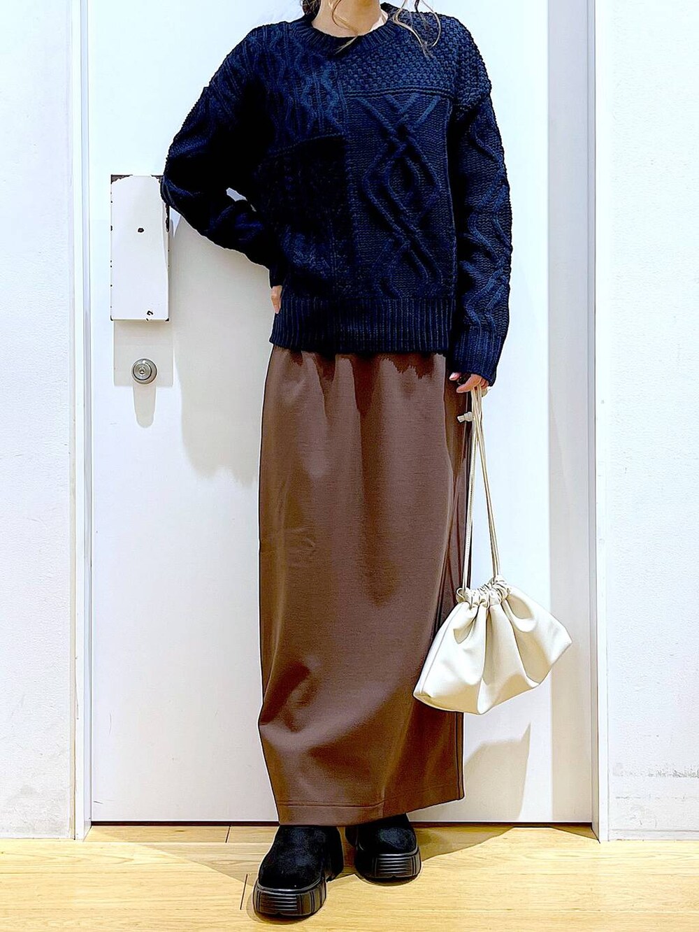 ブラック系のブーツ、ベージュ系のショルダーバッグ、ブラウン系のスカートを着用したレディースの冬コーディネートの6枚目の写真