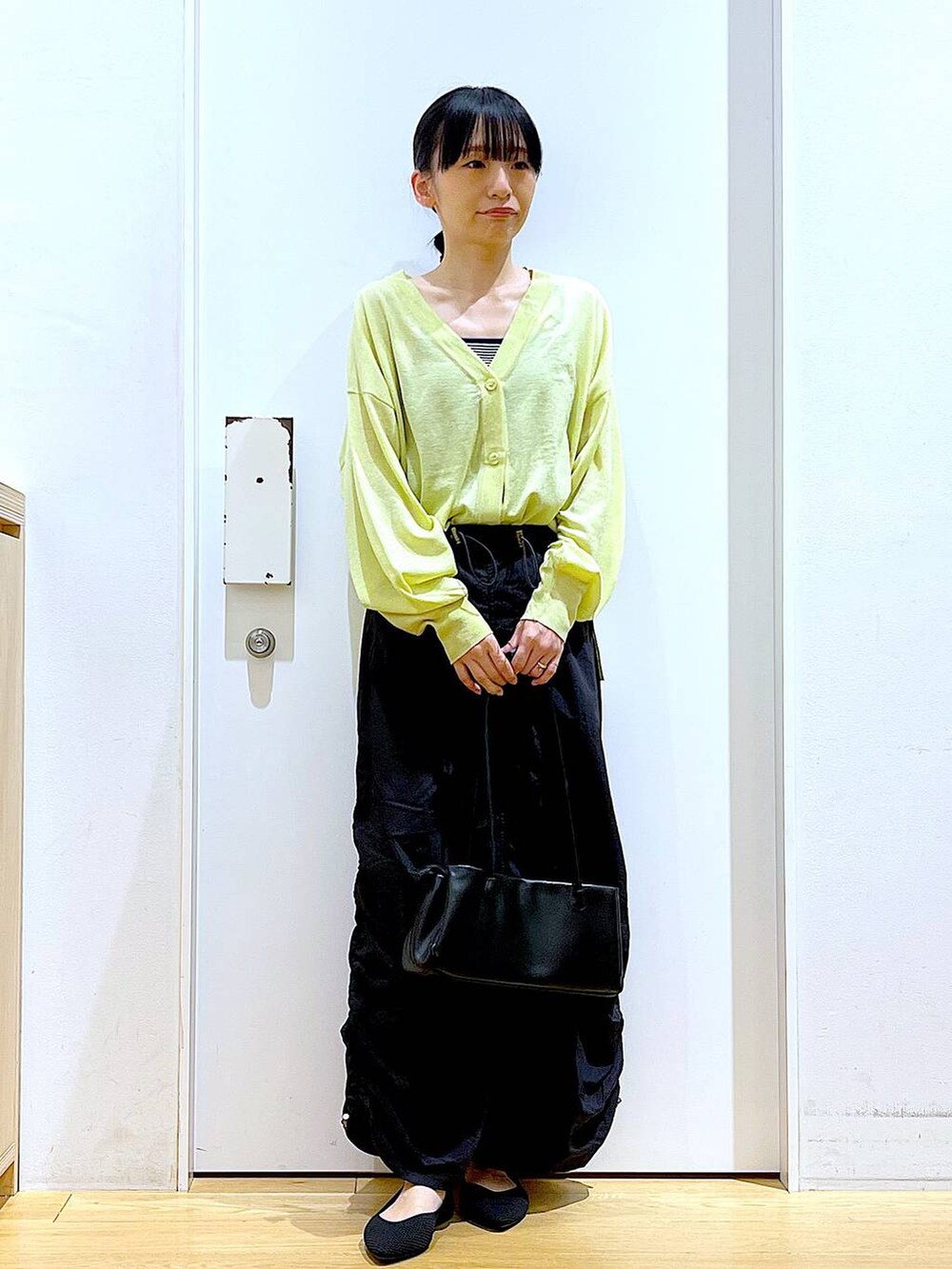 ホワイト系のキャミソール、グリーン系のカーディガン/ボレロ、ブラック系のトートバッグを着用したレディースの春コーディネートの2枚目の写真