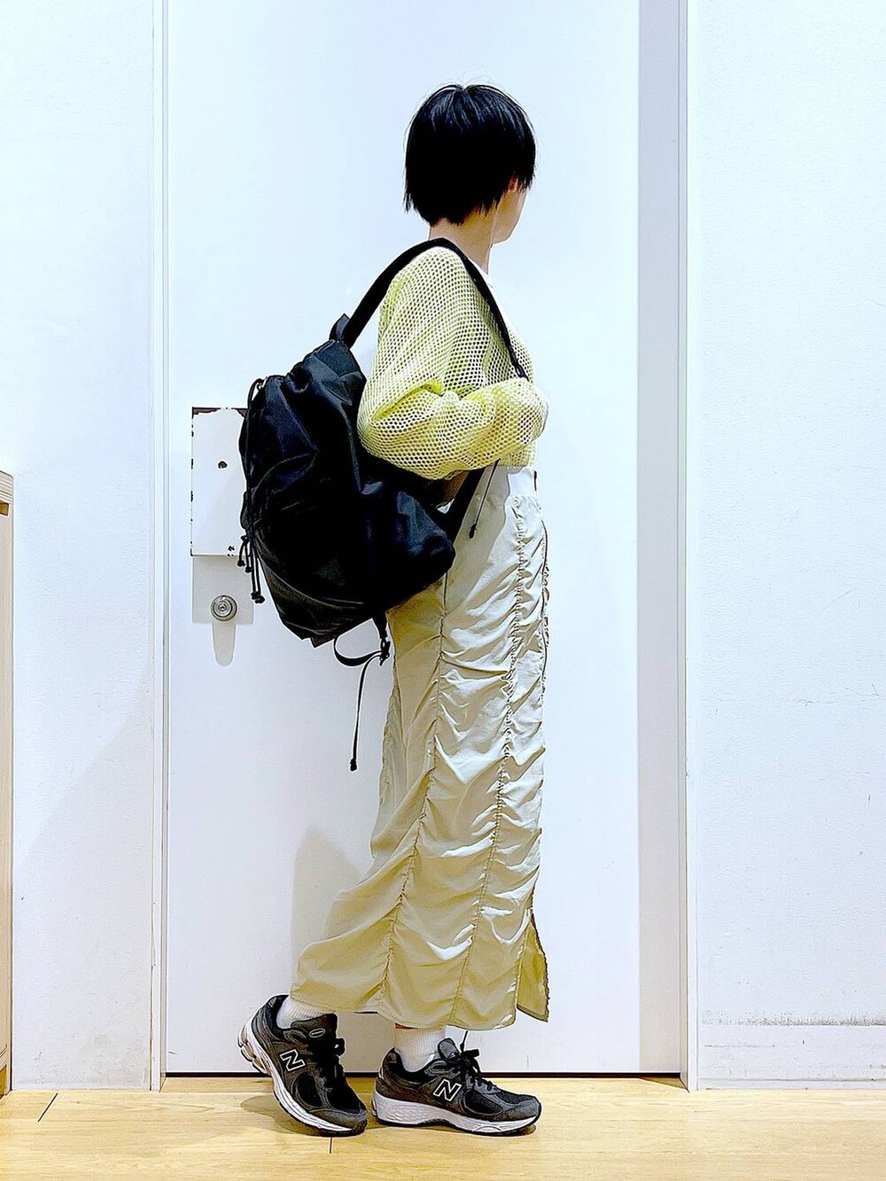ベージュ系のスカート、ブラック系のバックパック/リュック、イエロー系のTシャツ/カットソーを着用したレディースの春コーディネートの4枚目の写真