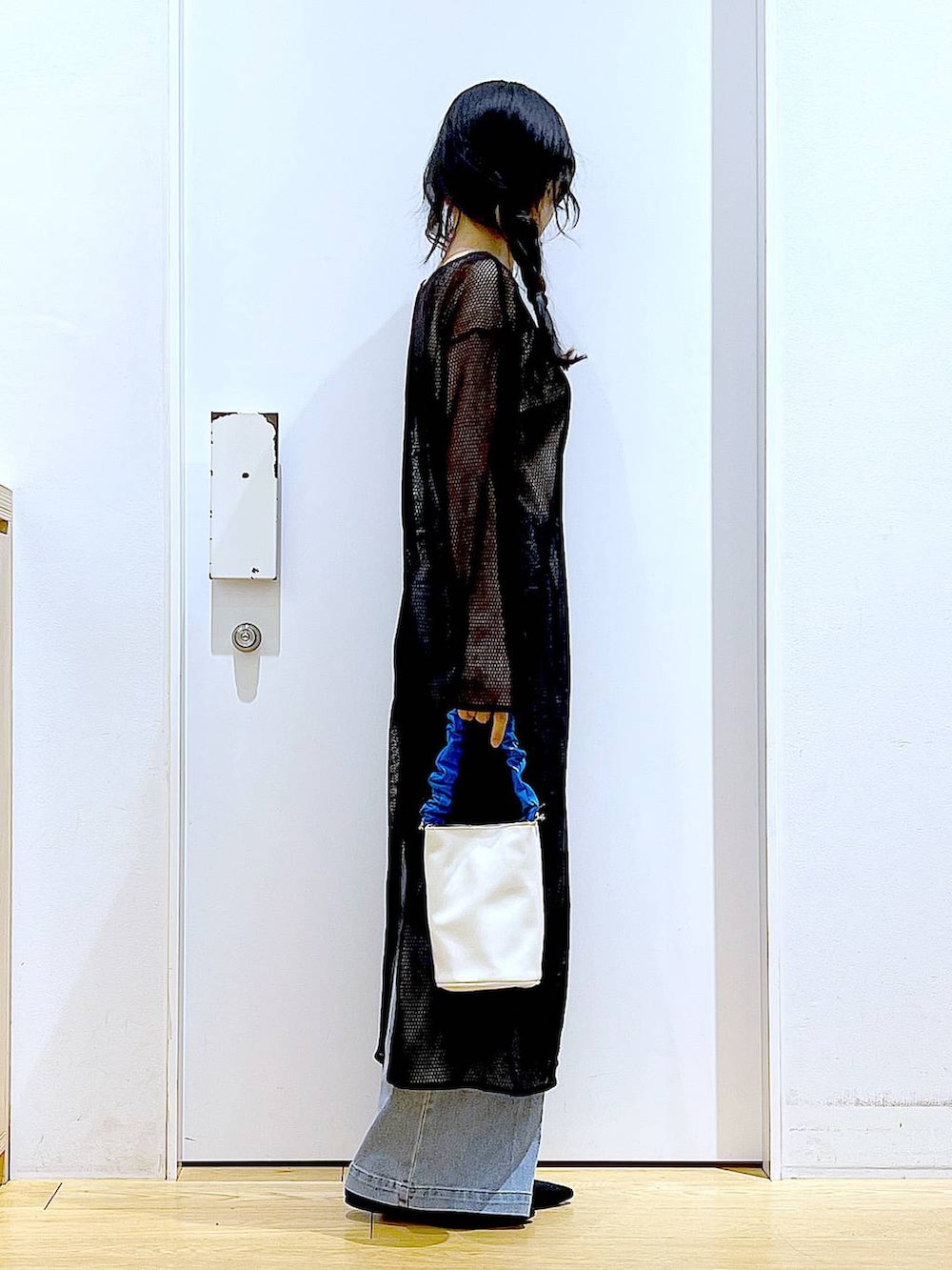 ブルー系のショルダーバッグ、ブラック系のパンプス、ブルー系のデニムパンツを着用したレディースの春コーディネートの4枚目の写真