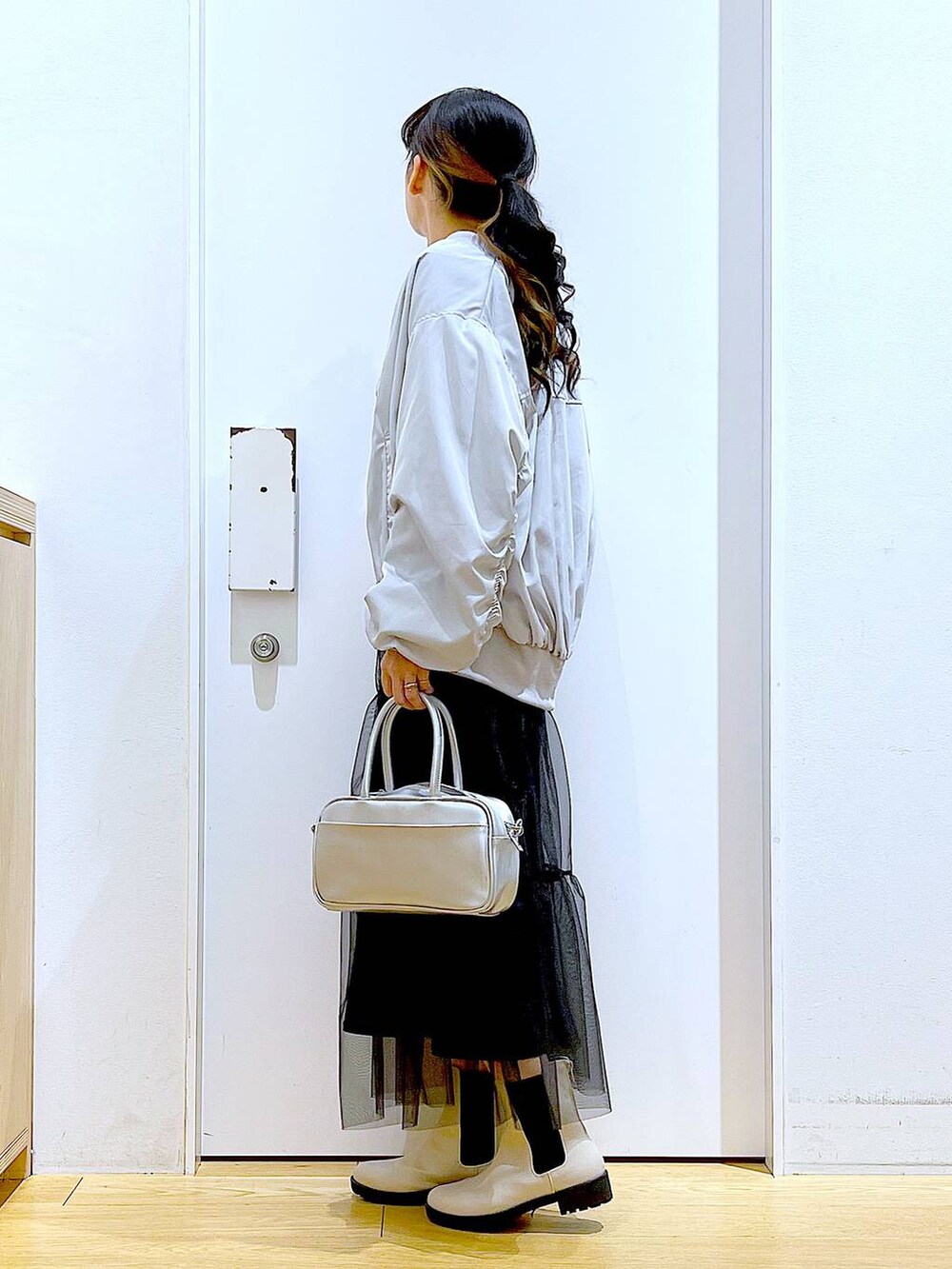 シルバー系のショルダーバッグ、グレー系のMA-1、ベージュ系のブーツを着用したレディースの春コーディネートの3枚目の写真