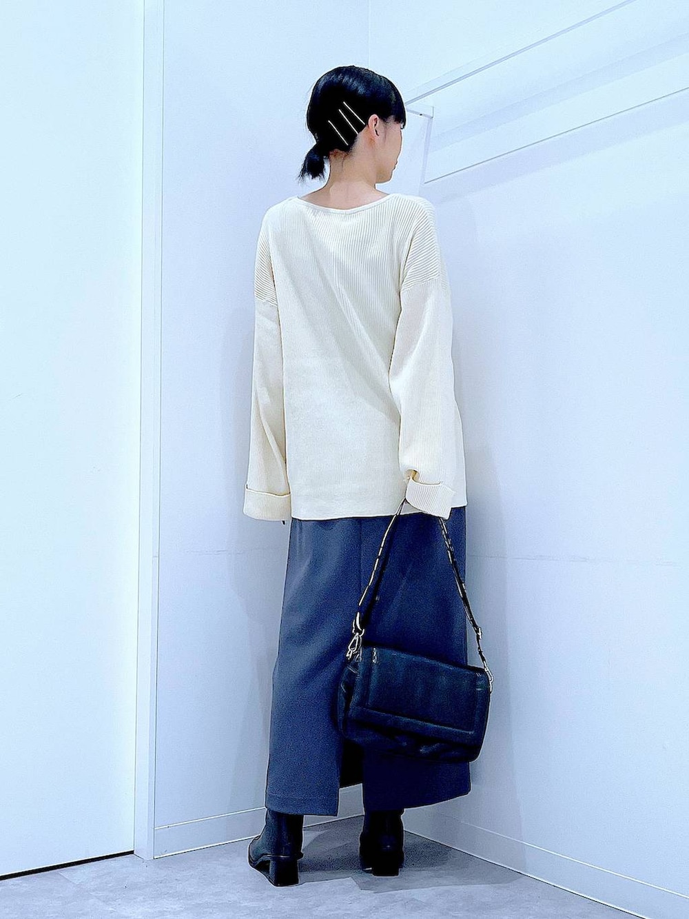 グレー系のスカート、ブラック系のショルダーバッグ、ブラック系のブーツを着用したレディースの冬コーディネートの5枚目の写真