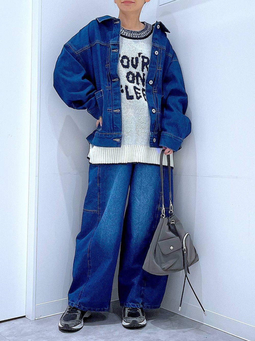 ブルー系のデニムジャケット、ホワイト系のニット/セーター、ブルー系のデニムパンツを着用したレディースの冬コーディネートの6枚目の写真