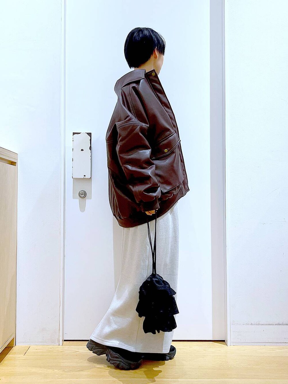 ブラウン系のブルゾン、ブラック系のブーツ、ブラック系のショルダーバッグを着用したレディースの冬コーディネートの4枚目の写真