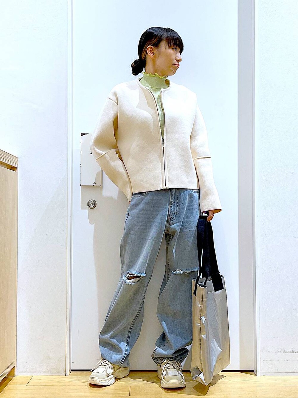 グリーン系のTシャツ/カットソー、ベージュ系のスニーカー、ブルー系のデニムパンツを着用したレディースの冬コーディネートの2枚目の写真