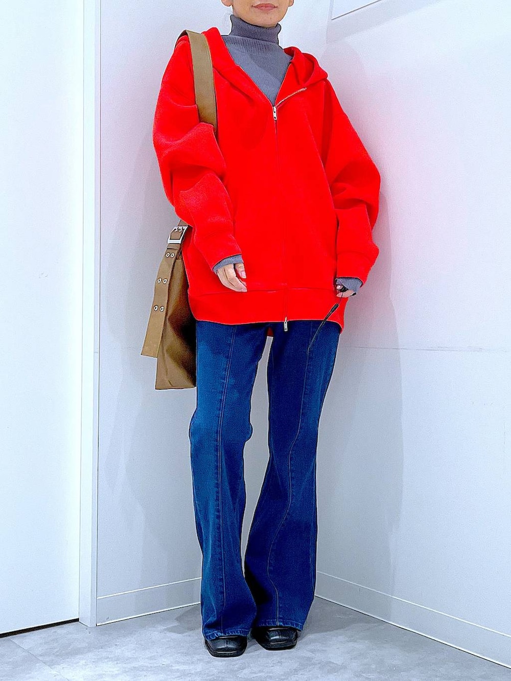 レッド系のパーカー、ブラック系のブーツ、グレー系のニット/セーターを着用したレディースの冬コーディネートの6枚目の写真