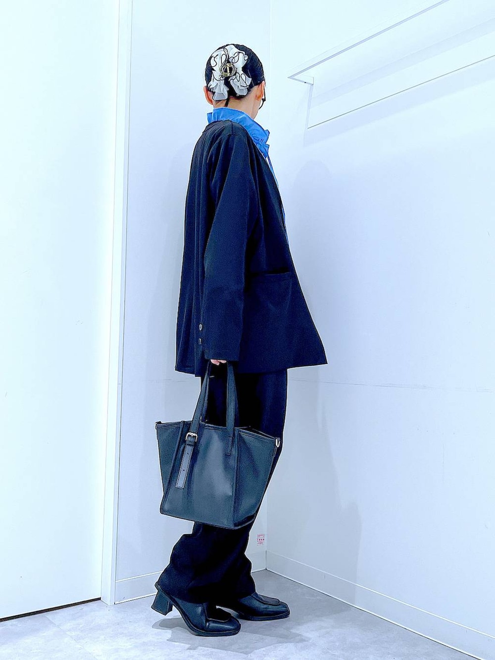 ブラック系のブーツ、ブラック系のトートバッグ、ブラック系のノーカラージャケットを着用したレディースの冬コーディネートの4枚目の写真