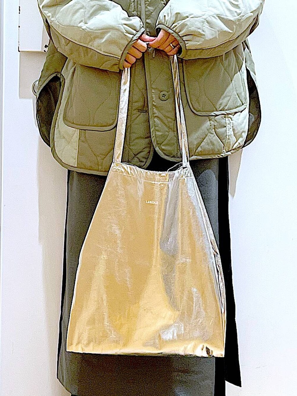 シルバー系のトートバッグ、グレー系のスカート、ブラック系のブーツを着用したレディースの秋コーディネートの9枚目の写真