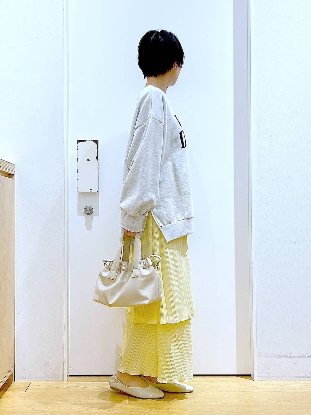 ホワイト系のショルダーバッグ、ホワイト系のパンプス、ベージュ系のスウェットを着用したレディースの冬コーディネートの4枚目の写真