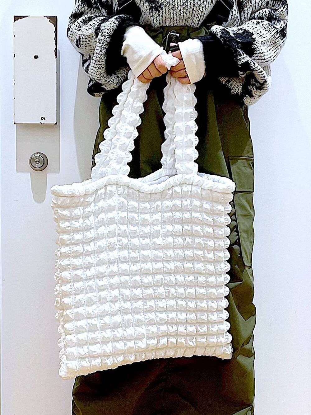 ホワイト系のトートバッグ、ベージュ系のTシャツ/カットソー、グリーン系のジャンパースカートを着用したレディースの冬コーディネートの9枚目の写真