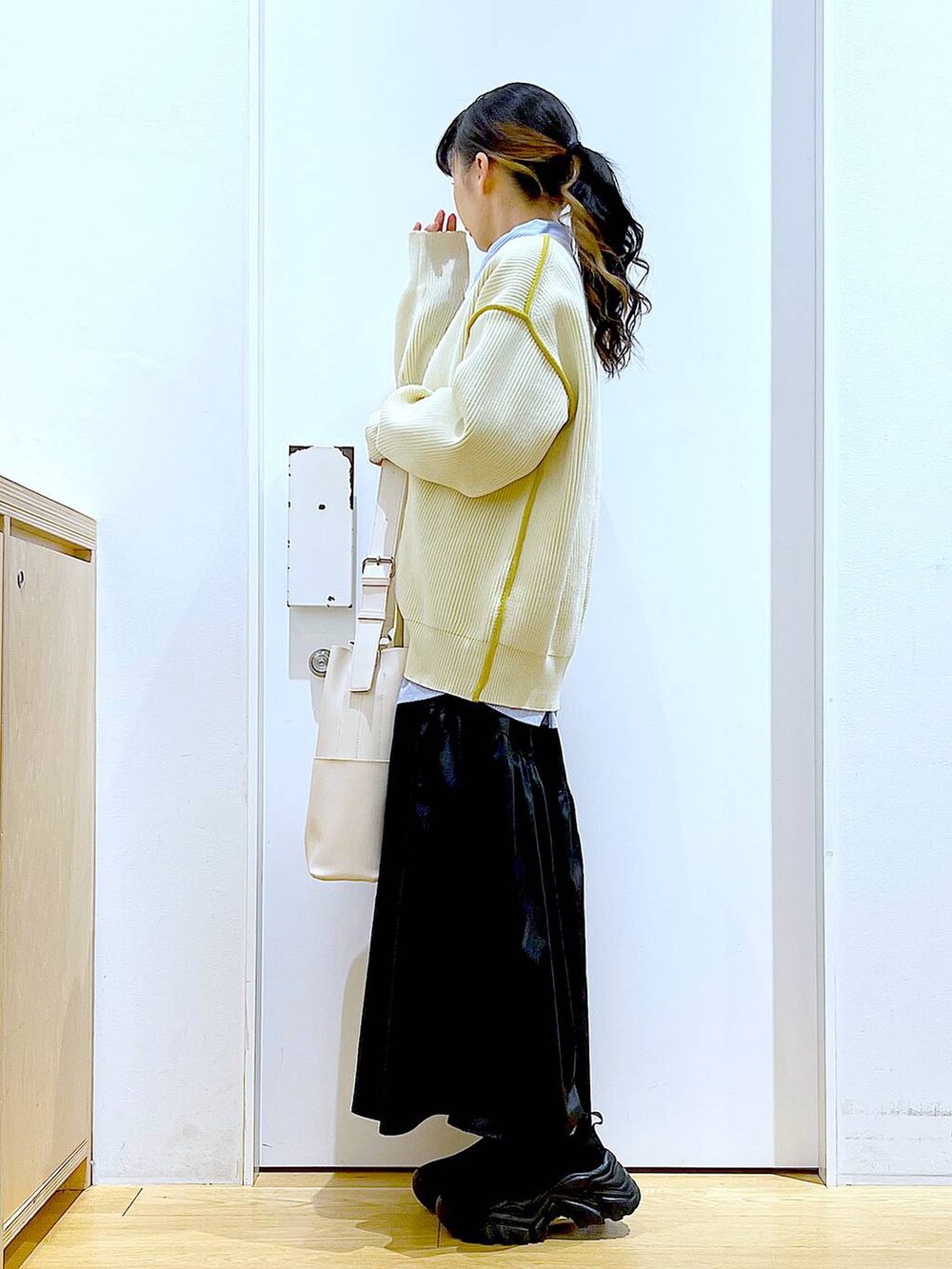 ホワイト系のショルダーバッグ、ホワイト系のカーディガン/ボレロ、ブラック系のスカートを着用したレディースの春コーディネートの3枚目の写真