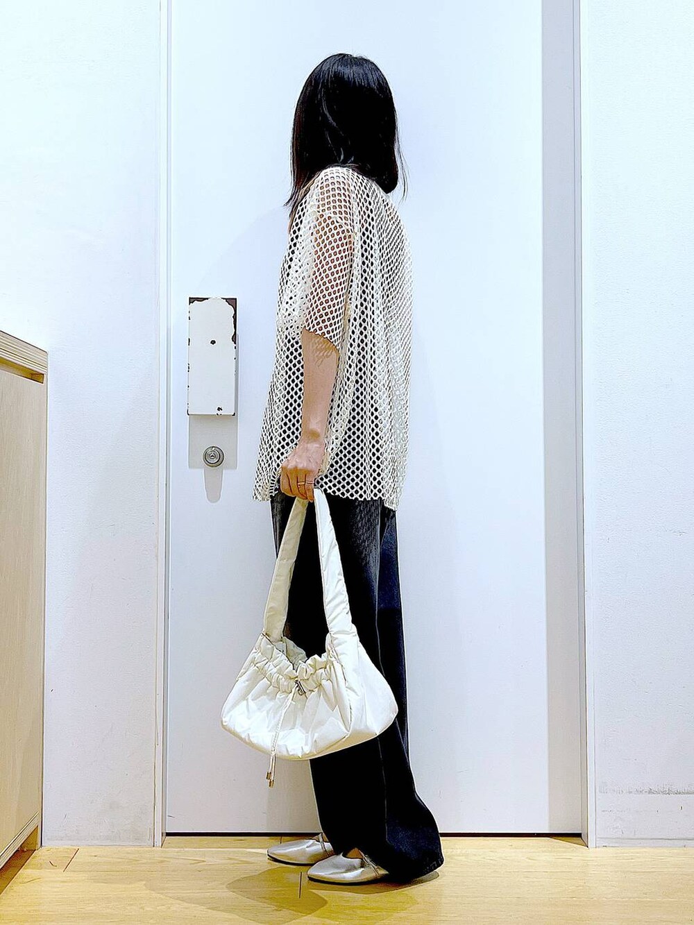 ホワイト系のハンドバッグ、ブラック系のニット/セーター、ホワイト系のTシャツ/カットソーを着用したレディースの夏コーディネートの3枚目の写真