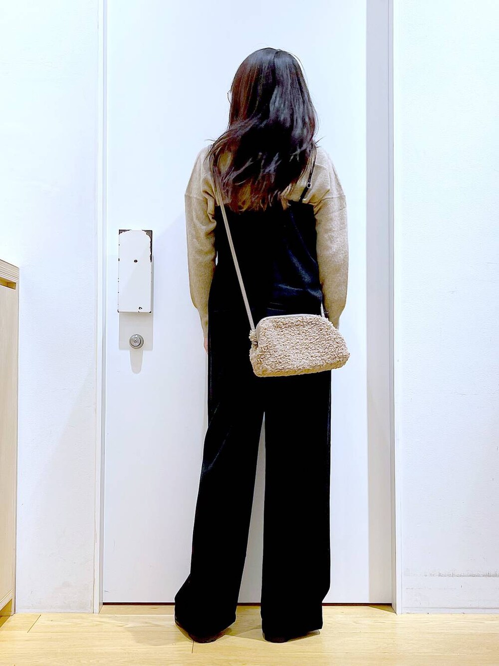 ベージュ系のニット/セーター、ブラック系のブーツ、ブラウン系のクラッチバッグを着用したレディースの冬コーディネートの5枚目の写真