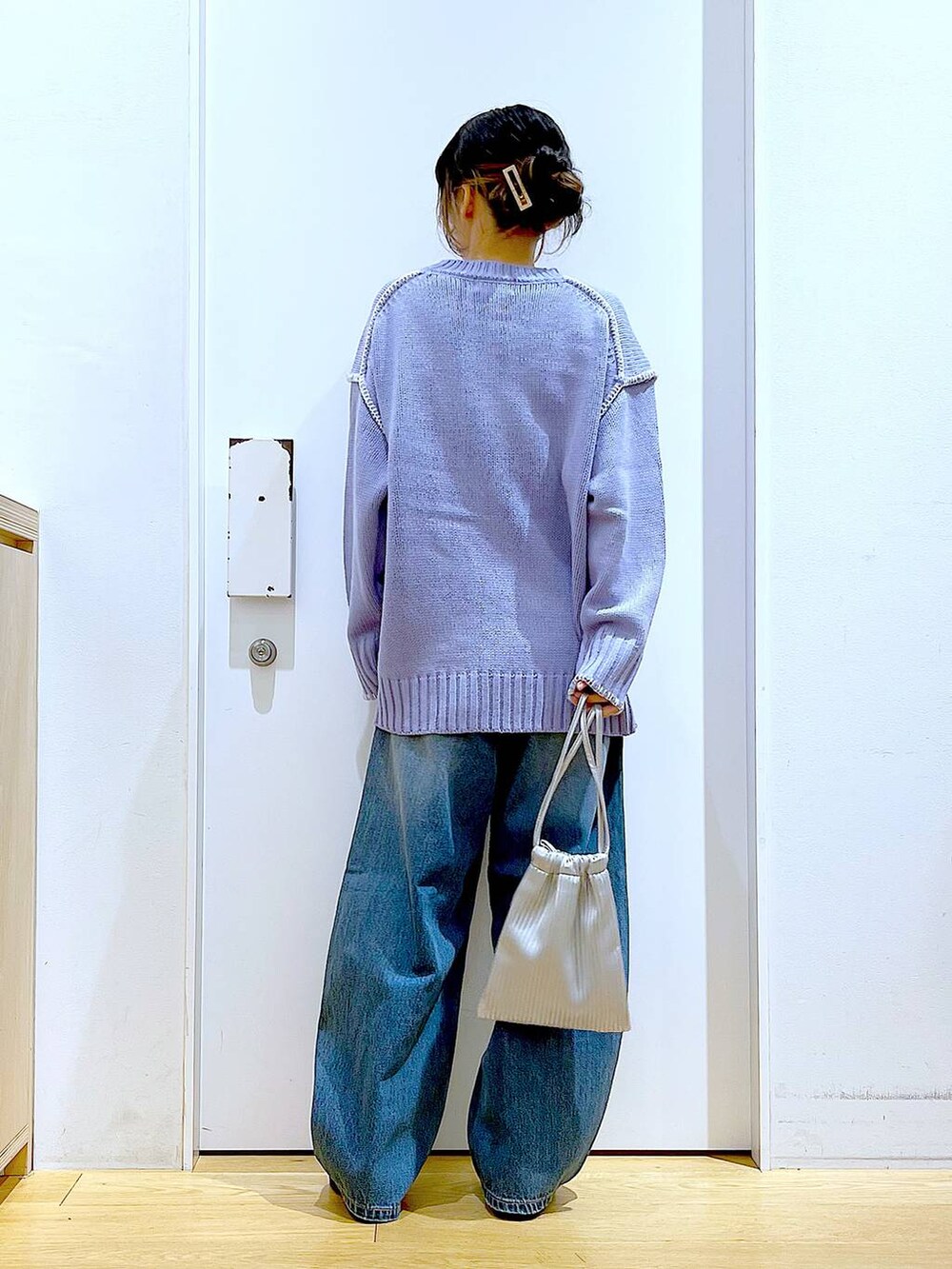 シルバー系のショルダーバッグ、ベージュ系のブーツ、ブルー系のデニムパンツを着用したレディースの冬コーディネートの5枚目の写真