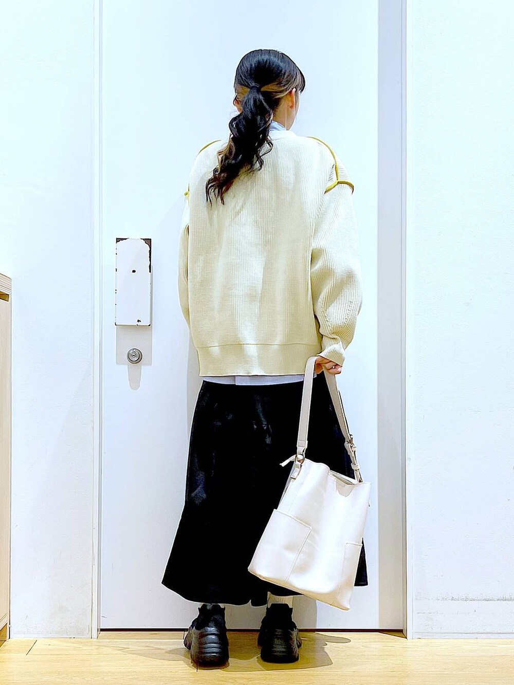 ホワイト系のショルダーバッグ、ホワイト系のカーディガン/ボレロ、ブラック系のスカートを着用したレディースの春コーディネートの5枚目の写真