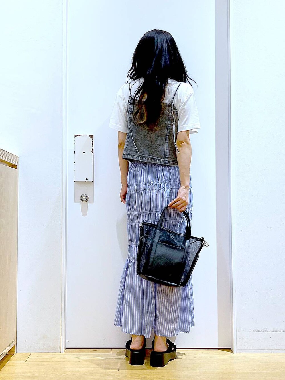 ブラック系のサンダル、ブラック系のトートバッグ、グレー系のベストを着用したレディースの夏コーディネートの5枚目の写真