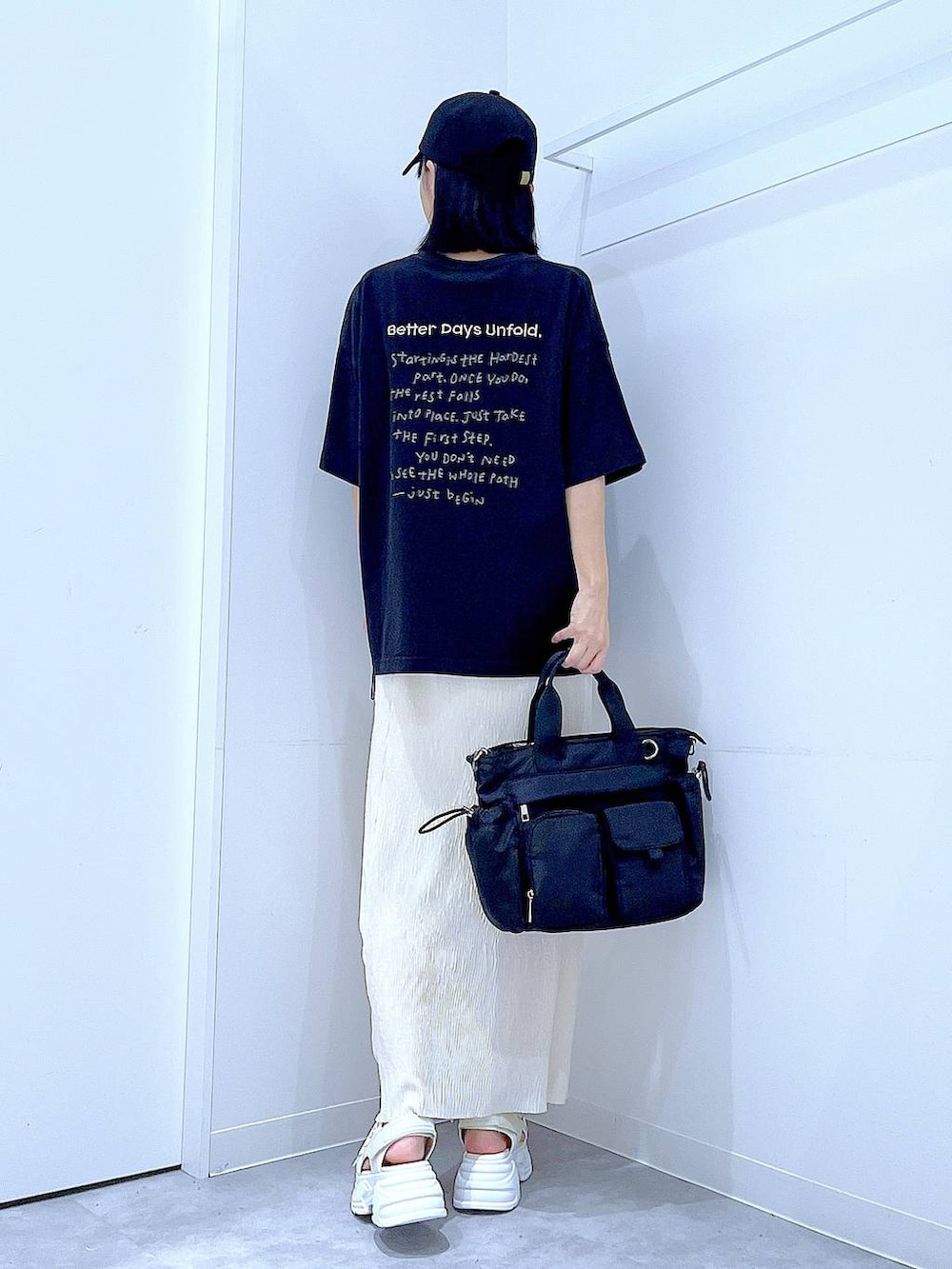 ブラック系のトートバッグ、ホワイト系のサンダル、ブラック系のTシャツ/カットソーを着用したレディースの夏コーディネートの5枚目の写真