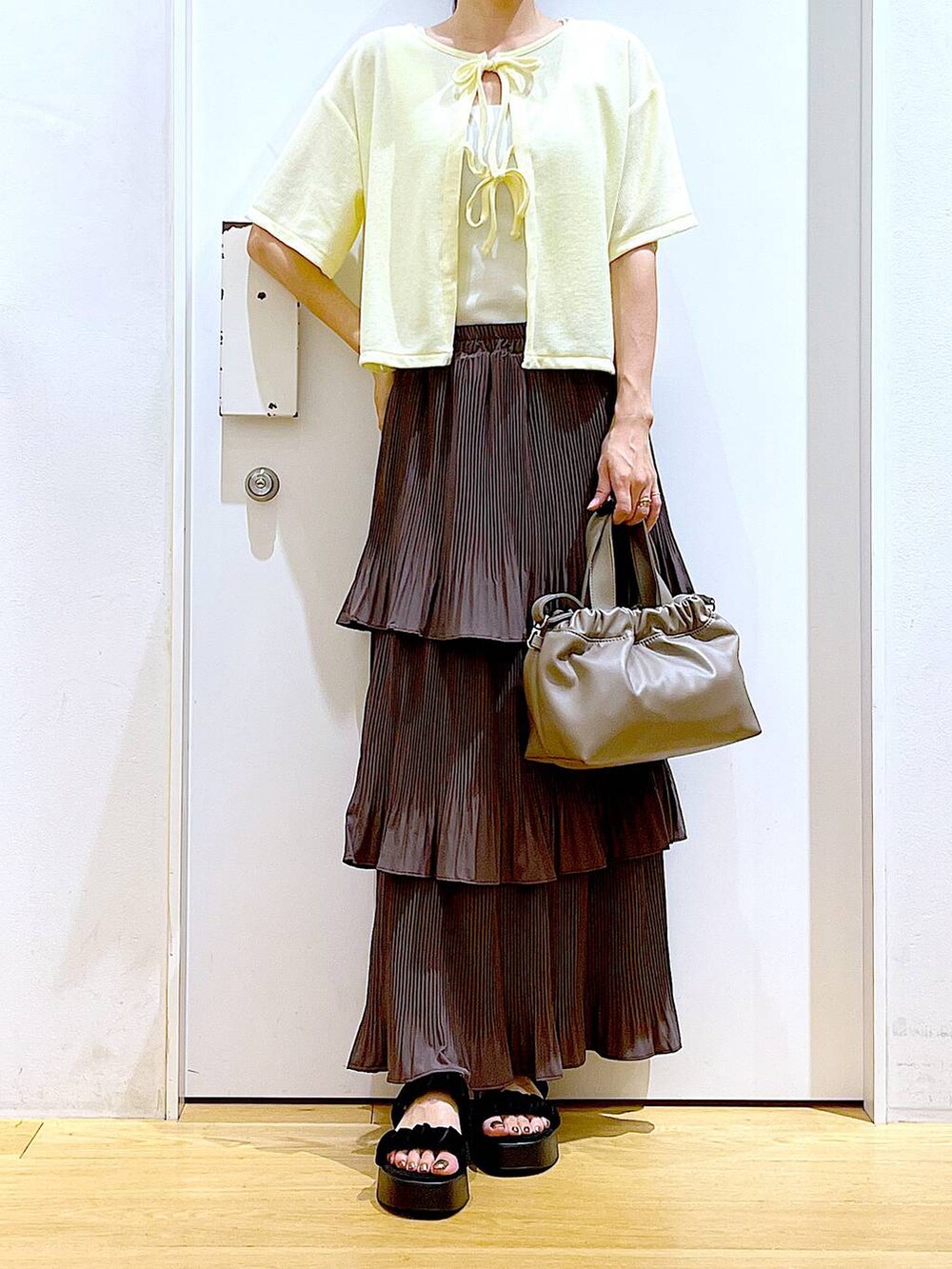 ブラウン系のスカート、ブラウン系のショルダーバッグ、ブラック系のサンダルを着用したレディースの秋コーディネートの6枚目の写真