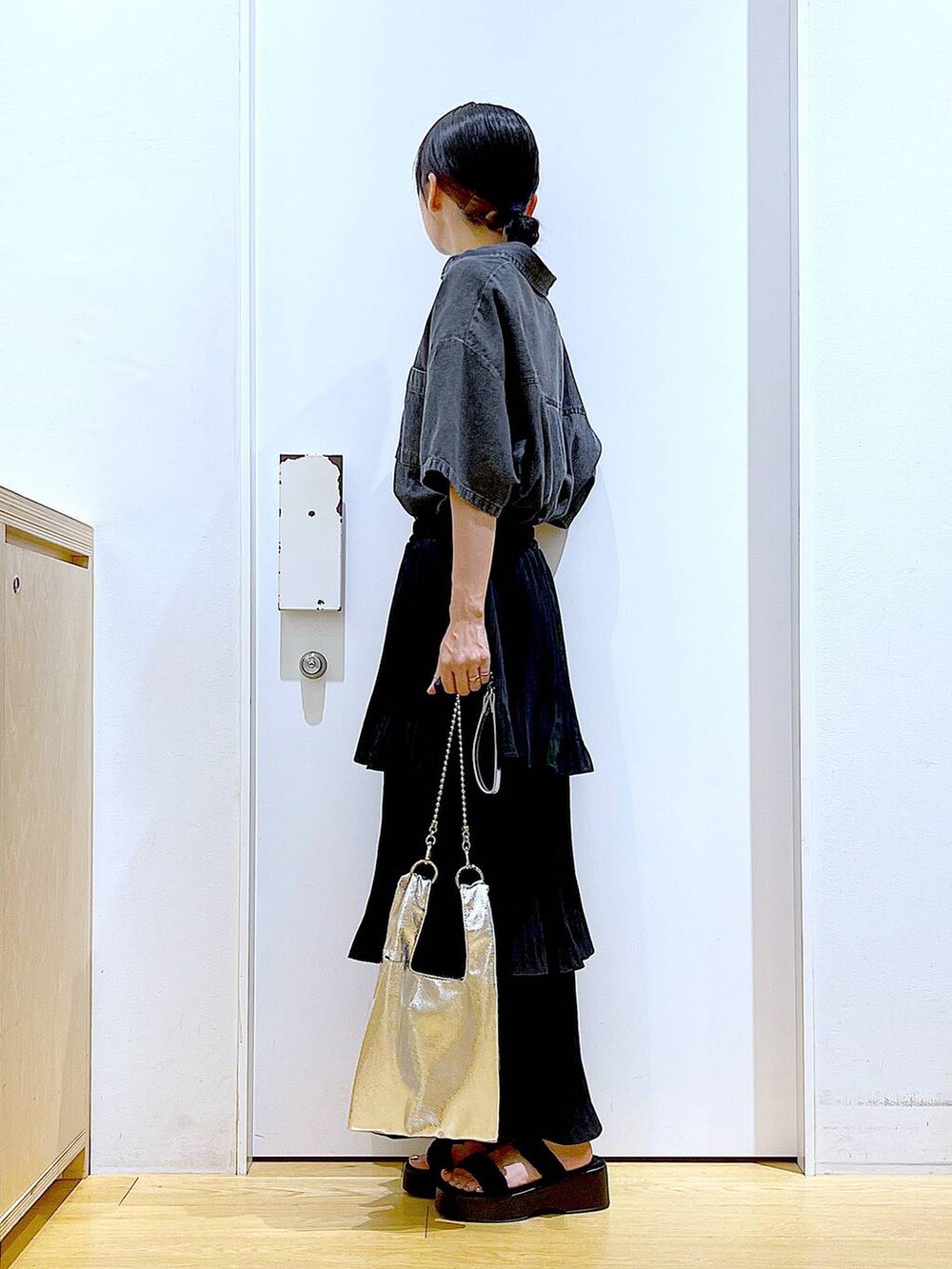 シルバー系のショルダーバッグ、ブラック系のスカート、ブラック系のサンダルを着用したレディースの夏コーディネートの3枚目の写真