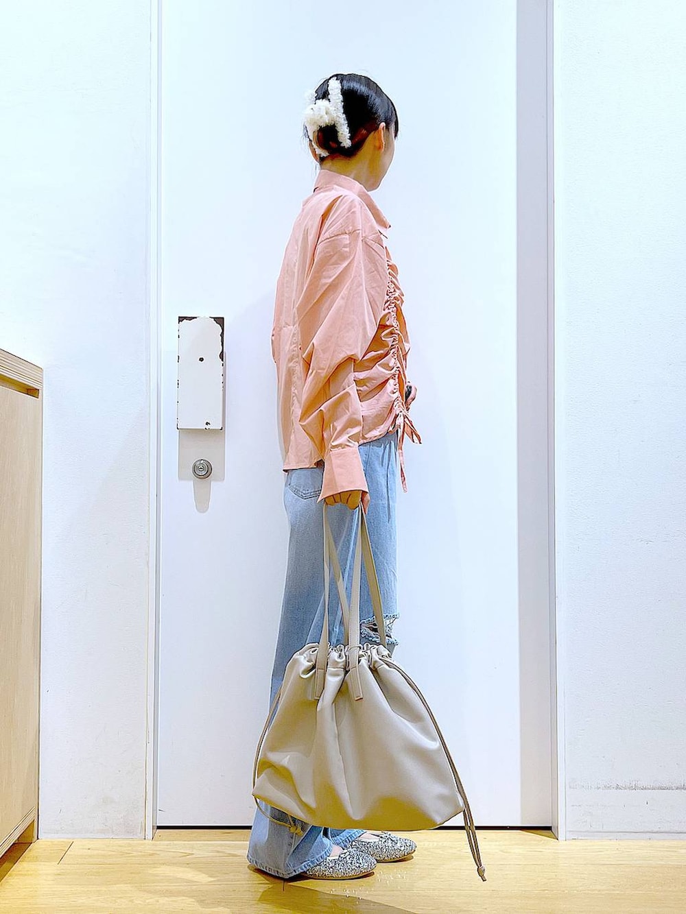 ベージュ系のトートバッグ、ブルー系のデニムパンツ、シルバー系のパンプスを着用したレディースの秋コーディネートの4枚目の写真