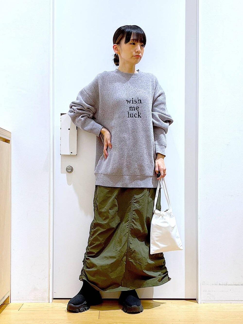 ブラック系のブーツ、グレー系のニット/セーター、グリーン系のスカートを着用したレディースの冬コーディネートの2枚目の写真