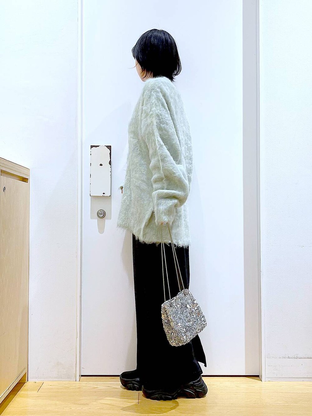 グリーン系のカーディガン/ボレロ、ブラック系のブーツ、ブラック系のスカートを着用したレディースの冬コーディネートの3枚目の写真