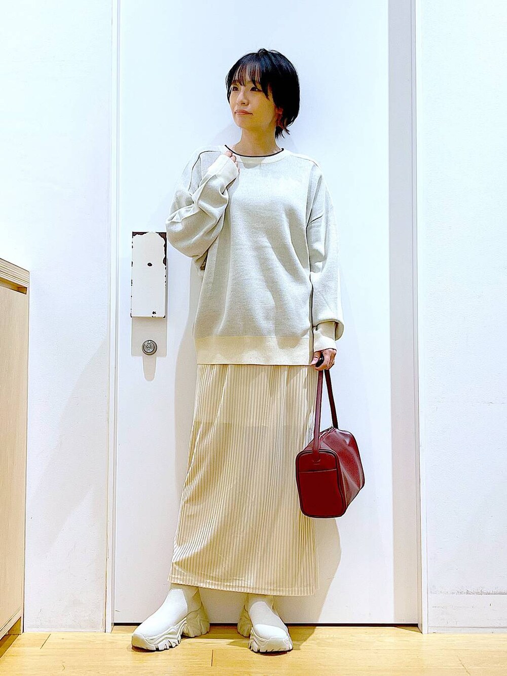 ベージュ系のニット/セーター、レッド系のショルダーバッグ、ベージュ系のブーツを着用したレディースの冬コーディネートの2枚目の写真