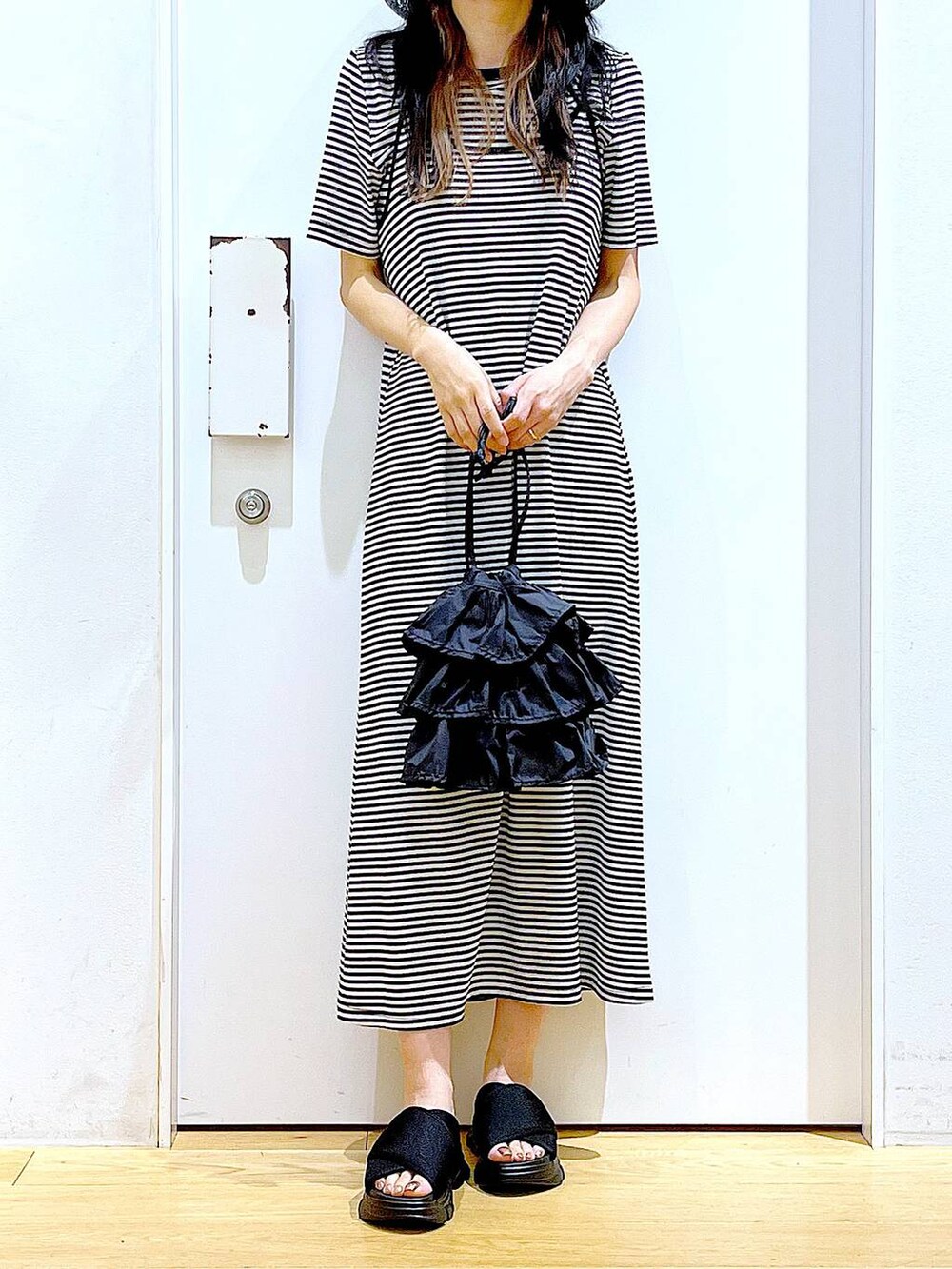 ブラック系のショルダーバッグ、ブラック系のサンダル、ブラック系のワンピースを着用したレディースの夏コーディネートの6枚目の写真