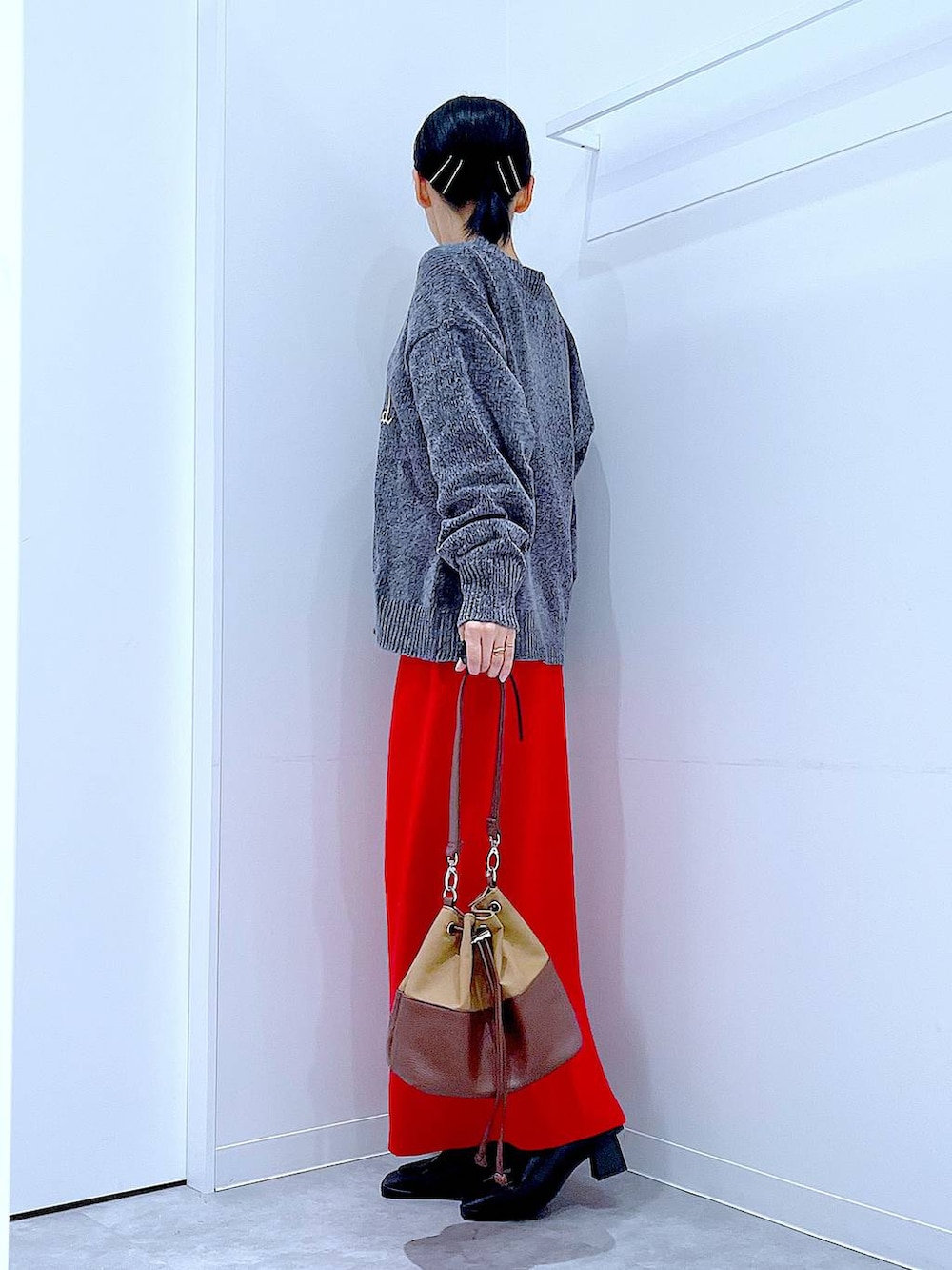 ベージュ系のショルダーバッグ、ブラック系のブーツ、グレー系のニット/セーターを着用したレディースの冬コーディネートの3枚目の写真