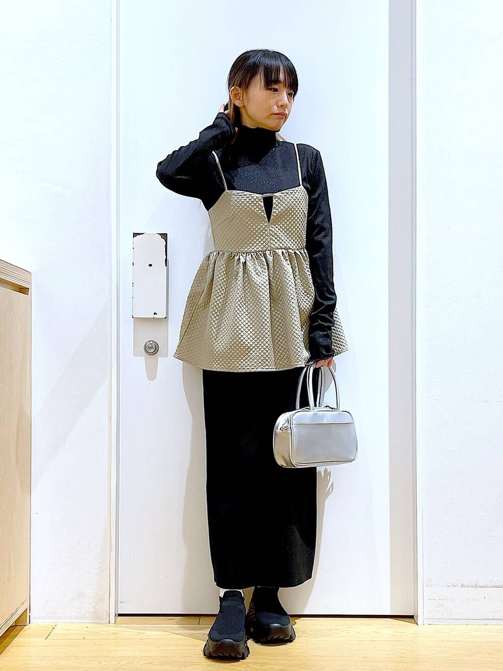 シルバー系のショルダーバッグ、ブラック系のTシャツ/カットソー、ブラック系のスニーカーを着用したレディースの春コーディネートの2枚目の写真