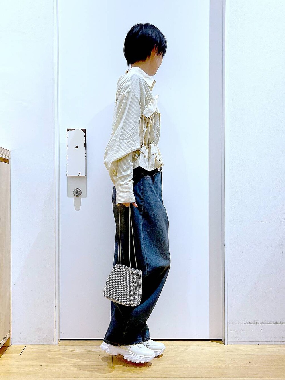 グレー系のショルダーバッグ、ブルー系のデニムパンツ、ホワイト系のスニーカーを着用したレディースの春コーディネートの4枚目の写真