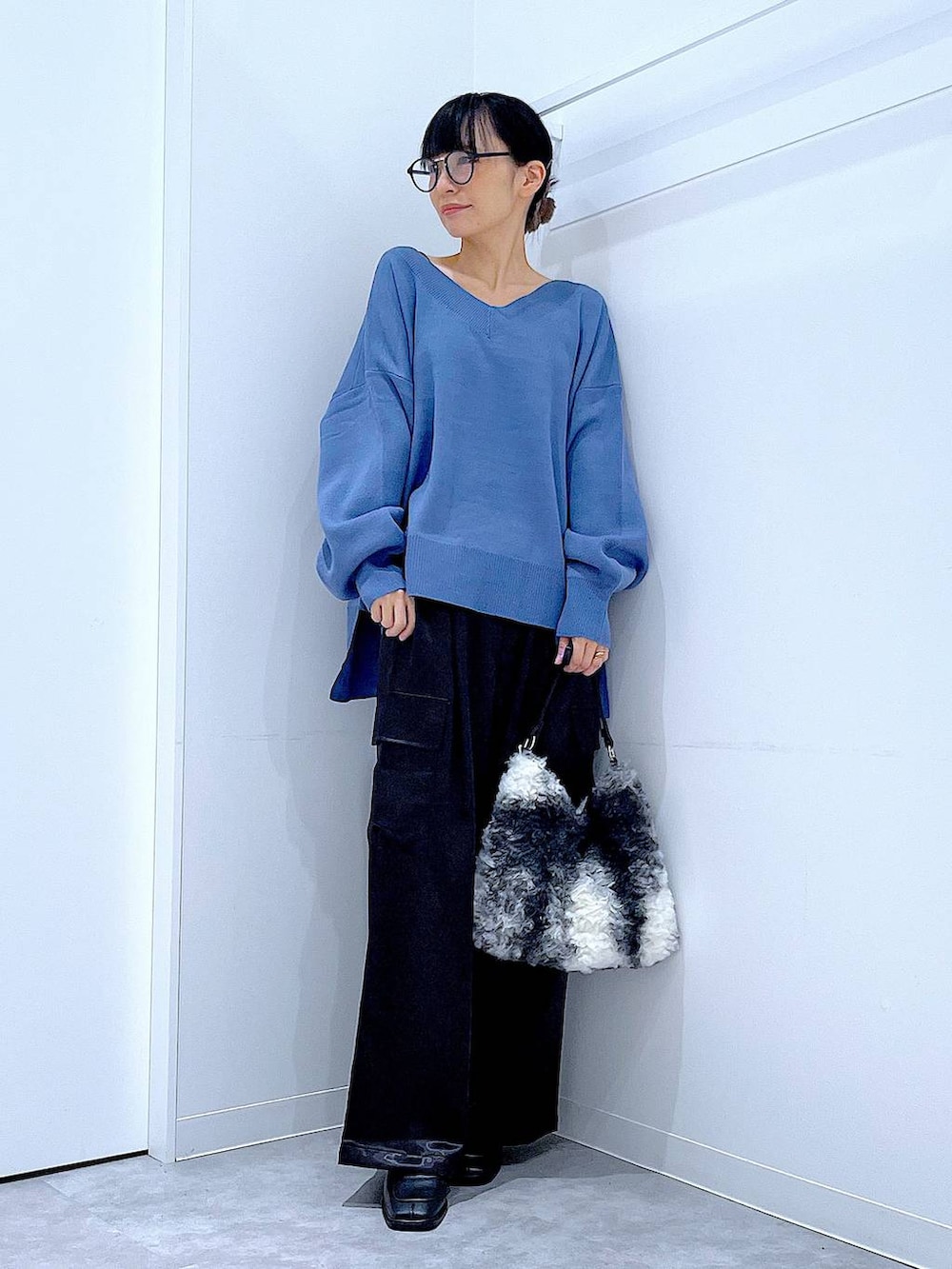 ブルー系のニット/セーター、ブラック系のブーツ、ブラック系のショルダーバッグを着用したレディースの冬コーディネートの2枚目の写真